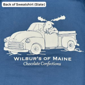 A crewneck in slate blue with a moose driving a truck. The text reads "Wilbur's of Maine Chocolate Confections"